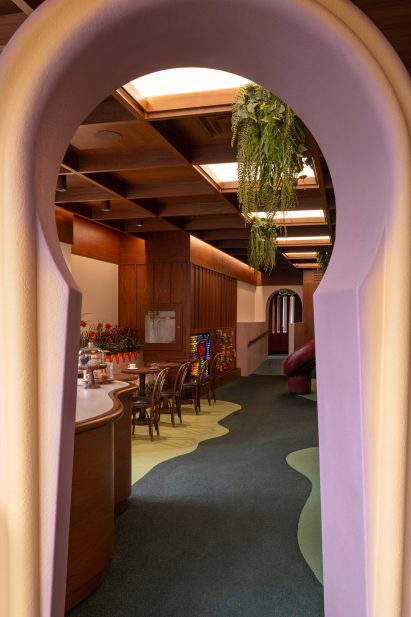 An arched portal with a key-shaped opening leads to a cafe and play area
