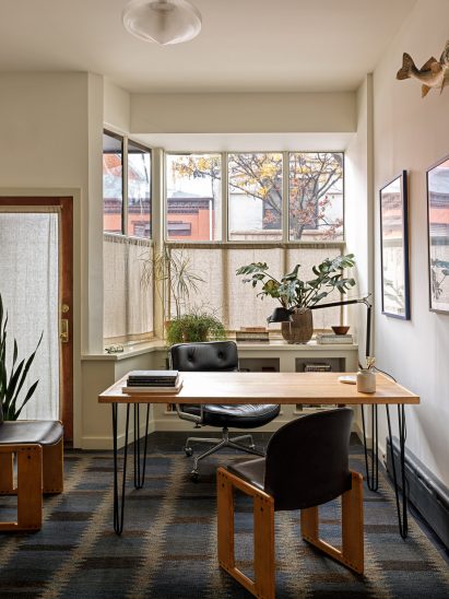 Office with storefront windows screened by cafe curtains and plants