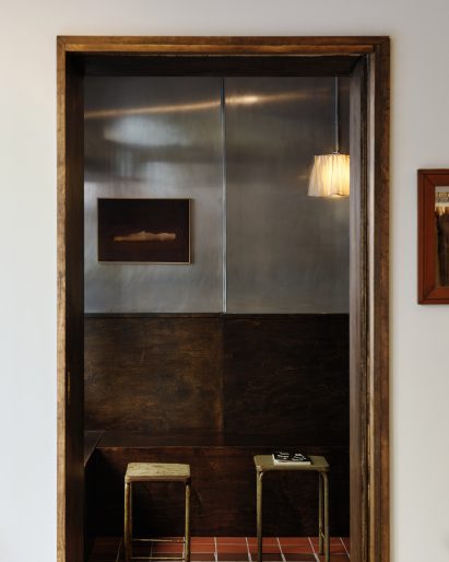 Doorway from an off-white room into a space with stainless steel and stained wood walls