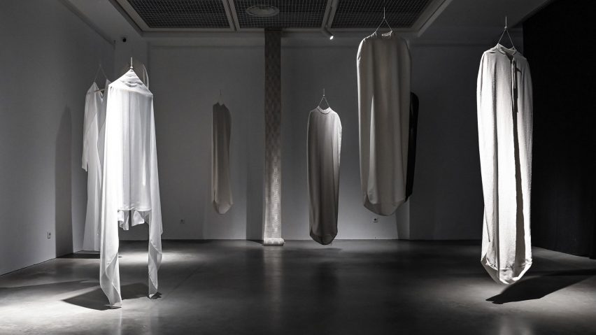 white garments hanging up in a black room