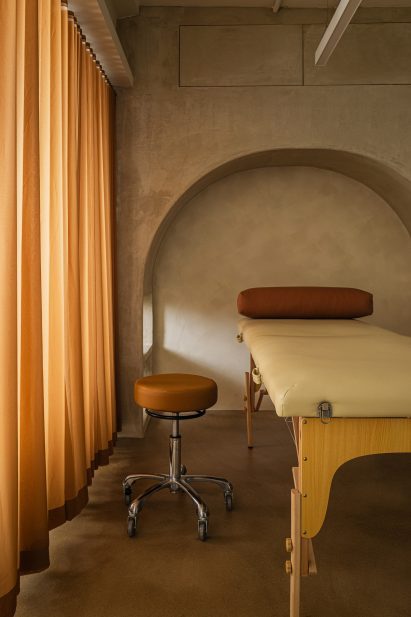 Tattoo station with an arched niche, a foldaway bed and a burnt-orange curtain