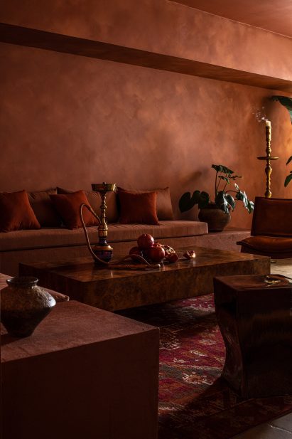 A dark red space where traditional Arabic rugs and decor items are mixed with contemporary furniture