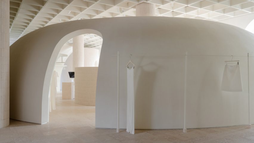 Image of a domed partition wall made from travertine, with a clothes rail wrapping around its exterior.
