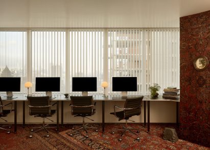 A custom system of stainless-steel desks runs below a window