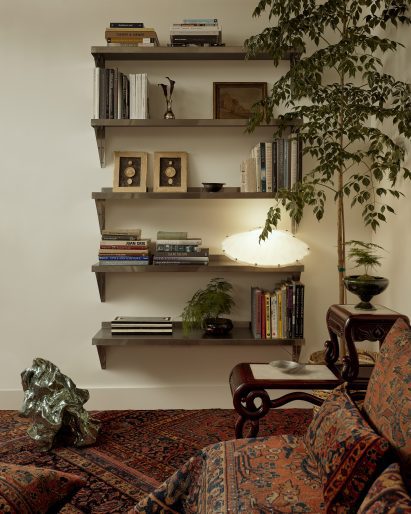 A series of stainless-steel shelves display books and small objects