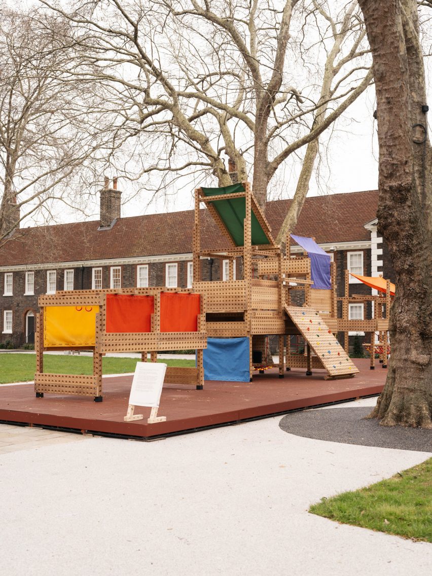 Wide shot of the Playrise playground showing a wooden structure with canopies and panels in different block colours pulled down in various sections