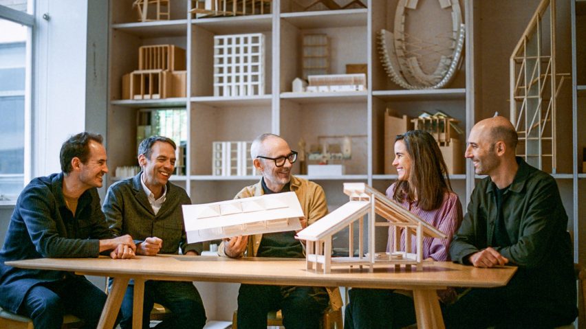 Photograph of people looking at architecture models around a table