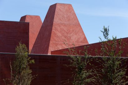 Close-up of the museum's pyramidal towers showing red pigmented concrete with herringbone-patterned formwork