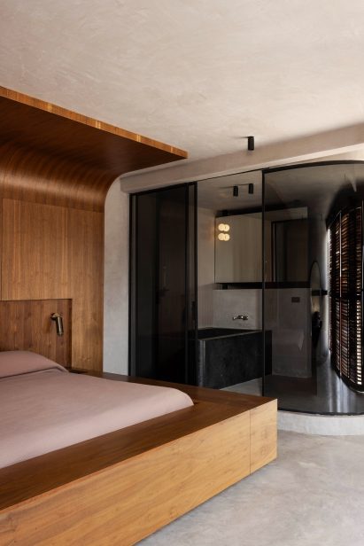 Dark-tinted glass curves around an en-suite bathroom