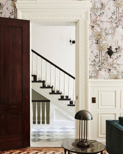 Doorway surrounded by intricate mouldings with a view to a staircase