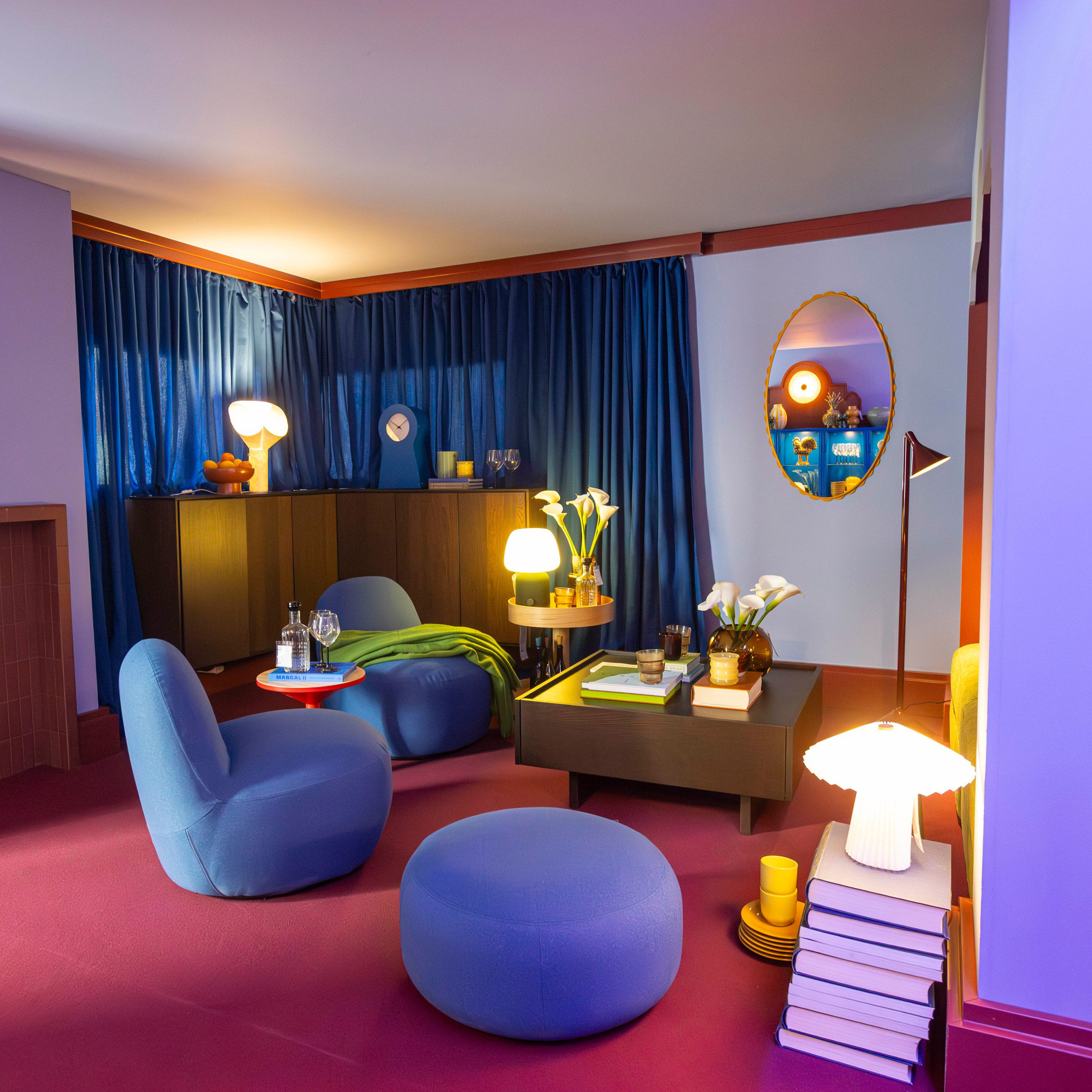 A living room set with blue seating, red flooring and warm lighting featured in IKEA’s Food for Thought exhibition in Milan