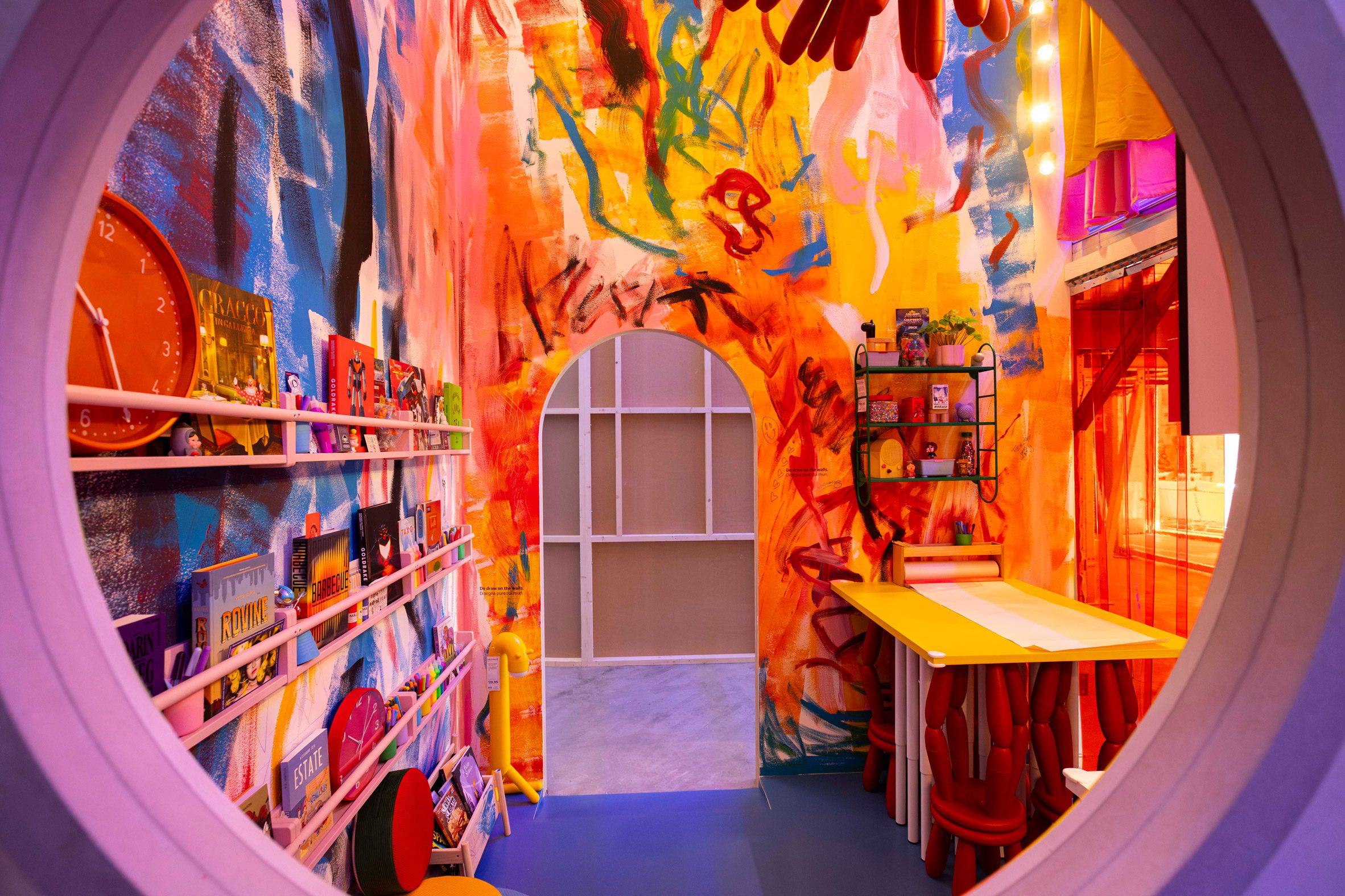 A colourful kitchen installation with hand-painted walls and a yellow worktable created for IKEA’s Food for Thought exhibition