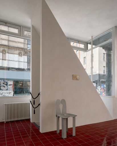 Triangular walls disguise a staircase bulkhead and provide a backdrop for an aluminium chair by Minjae Kim