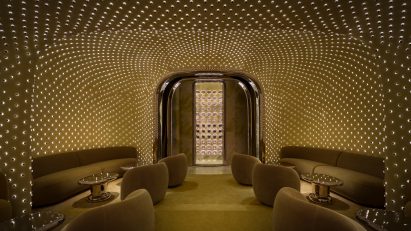 Curvaceous sofas are tucked into alcoves, and lights reflect off stainless steel tables and an arched door frame