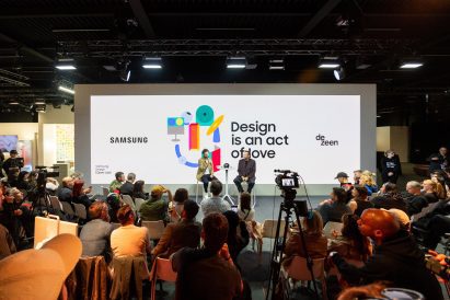 Audience watching Mauro Porcini and Benedict Hobson speaking on stage in front of a screen reading "Design is an act of love"