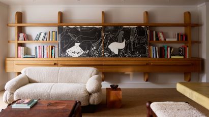 A custom-made bookshelf featuring a large John Gnorski sliding panel that hides a television and bar