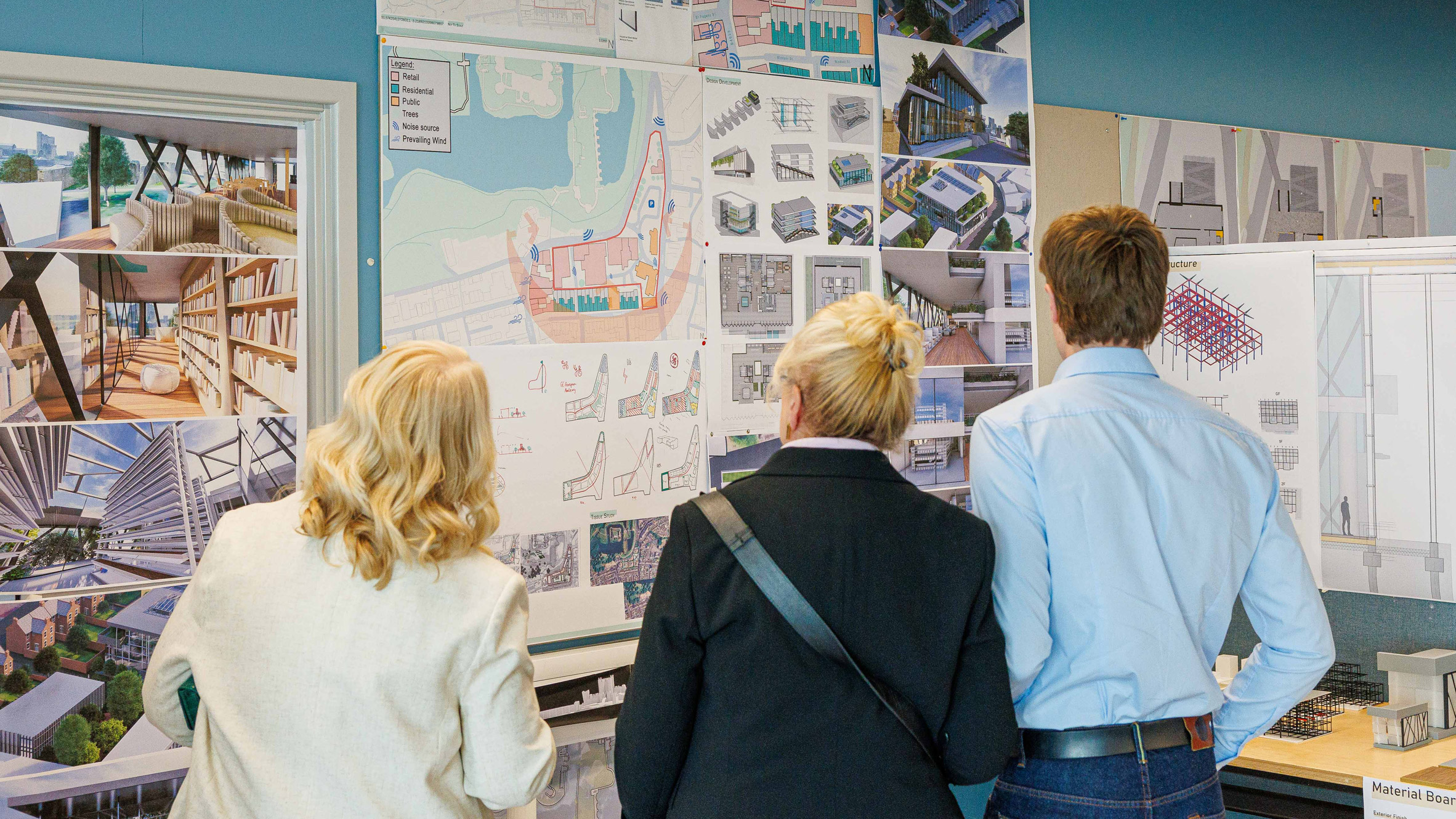 people looking at architecture work on a wall