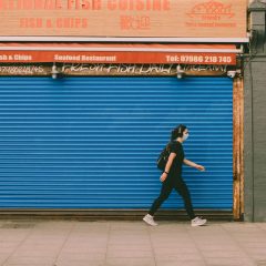 Woman with a Covid mask walking past a closed shop
