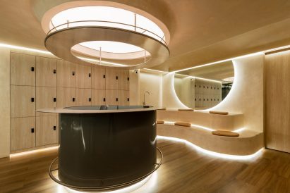 A glossy black volume sits below a circular luminaire in a locker room