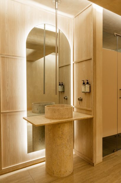 A cylindrical stone basin positioned in front of a large arched mirror