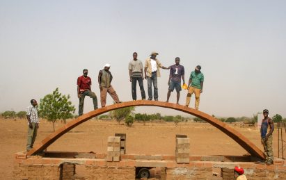 Kéré and builders standing on structural arch 