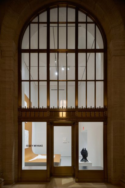 Exterior of a large arched window looking into a white gallery space