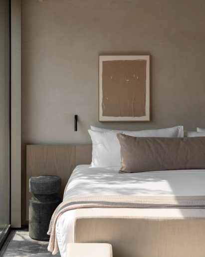 Guest room featuring volcanic stone flooring, pale wood furniture and beige plaster walls
