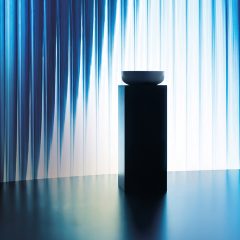 Ceramic basin displayed in front of a colourful light installation as part of the exhibition