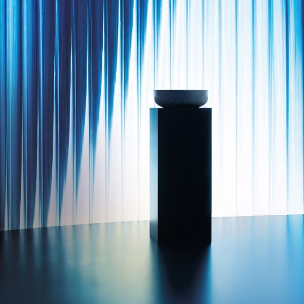 Ceramic basin displayed in front of a colourful light installation as part of the exhibition