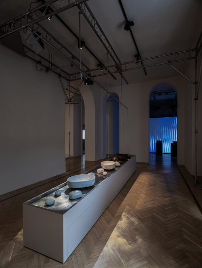 Long central installation with ceramic basins, stones and suspended streams of water