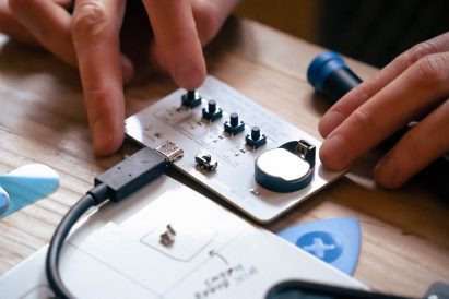 Close-up photo of a pair of hands playing with electronic components within the Team Repair Kit for Grown-Ups