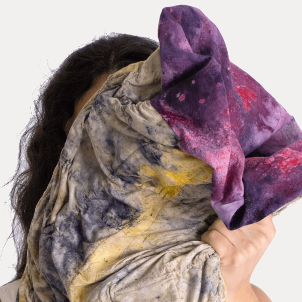 Person holding textile project up to face