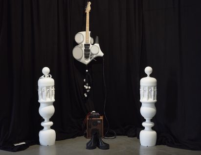 Photograph of an installation with music-related objects, including an amp and a stylised guitar.