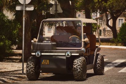Photo of the Amble One buggy in street legal mode with a box instead of a basket on the front, driving down a street