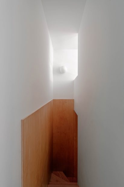 Plywood lines a narrow stairwell that leads to lower-level bedrooms