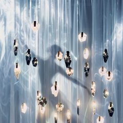 Silhouette of a dancer behind hanging glass lighting pieces and sheer fabric curtains
