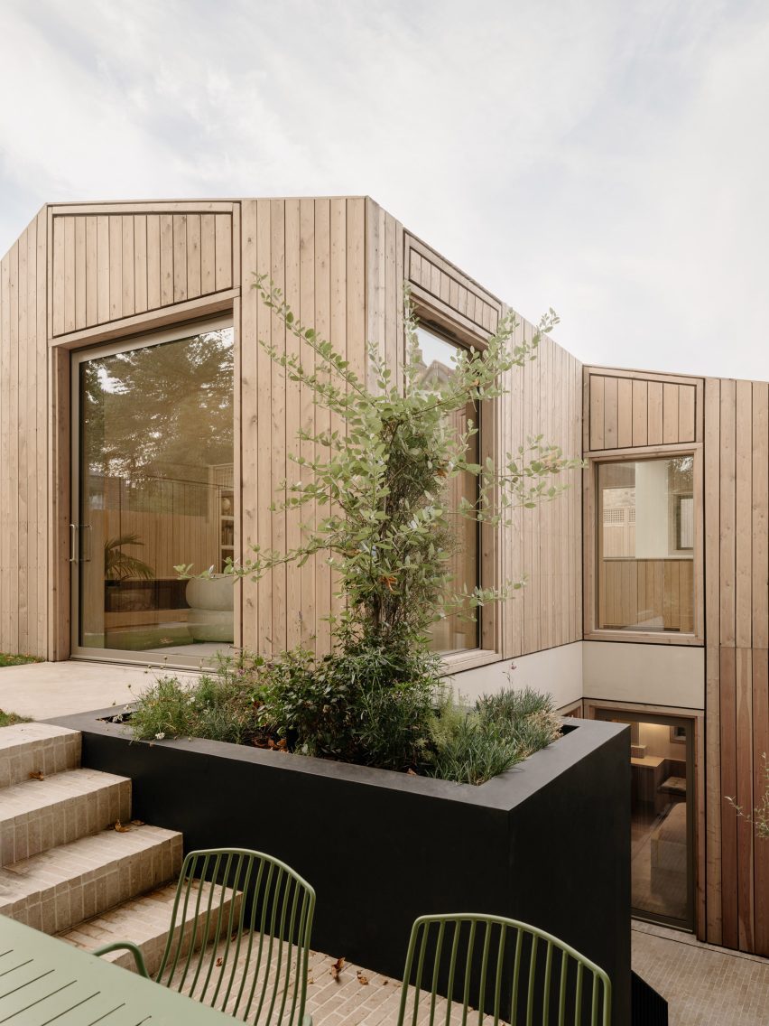 Outdoor terrace beside a planted lightwell, with steps leading to the upper level of the house