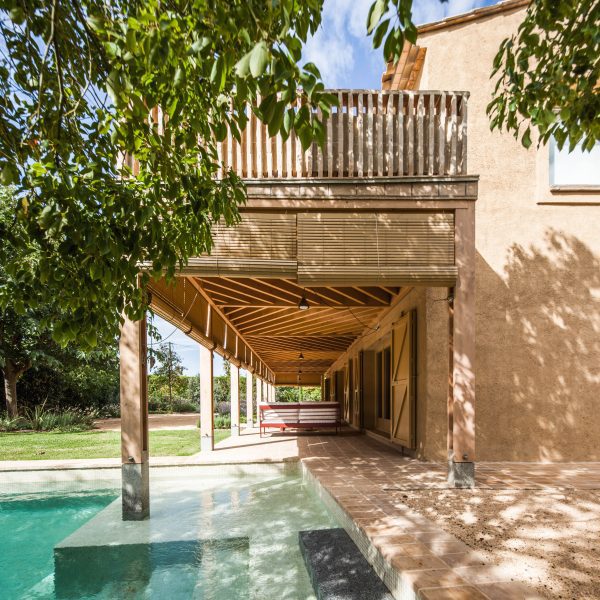 Timber porch with bamboo blinds extends over the edge of an existing swimming pool