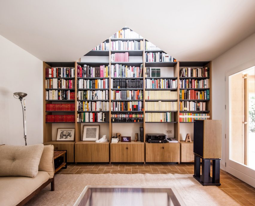 Built-in library shelves framed by a triangular opening beneath the roof