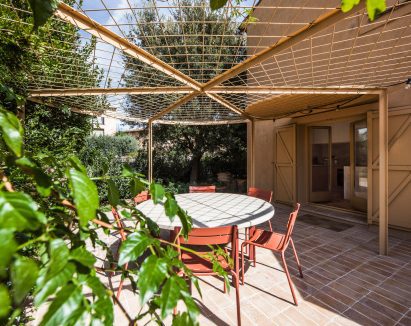 Circular pergola shading an outdoor dining area beside the house