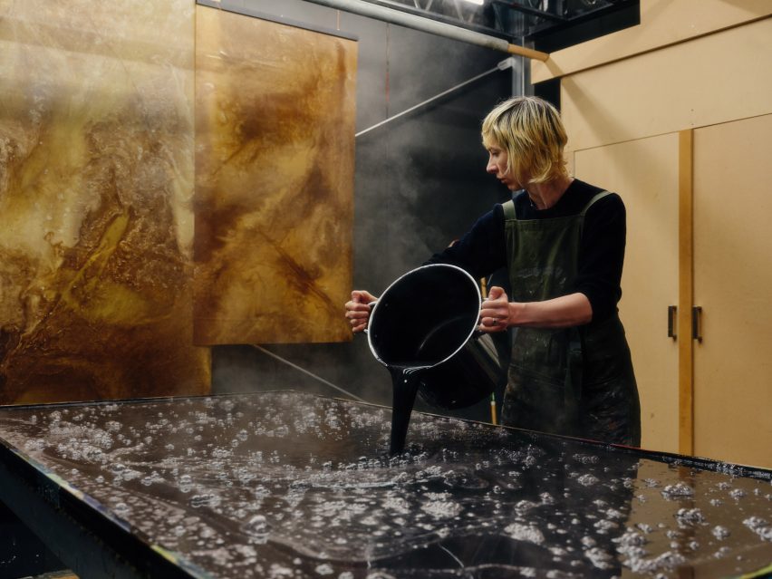Photo of Jessie French pouring bioplastic mixture into large trays to make Other Matter Leather
