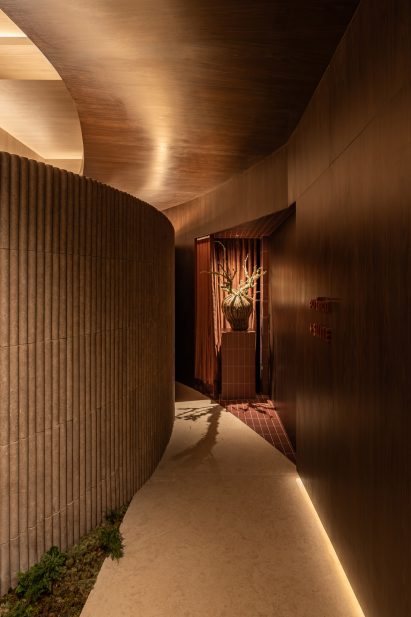 A corridor defined by a curved, fluted-tile partition