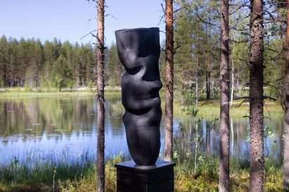 Photo of Ranti Bam's Climate Clock artwork showing a monumental black ceramic vessel sculpted with soft folds on the shore of a lake