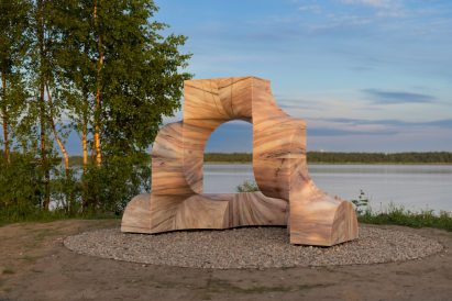 Photo of the Super Kello pink marble sculpture by a harbour surrounded by trees and grass