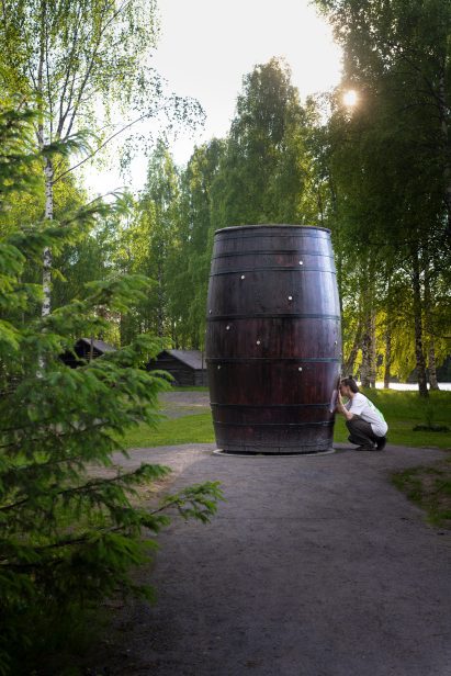 Photo of a person kneeling to peer into an eyehole on Takahiro Iwasaki three-metre-tall barrel artwork Architectural Snowflakes: Letters from Heaven
