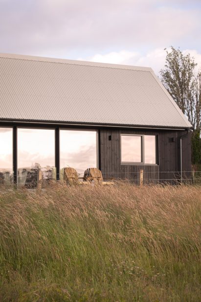 Blackened-larch extension with large sliding glass doors opening onto a raised patio