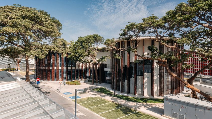 Exterior view of a low-rise library with an undulating concrete roof set among mature trees