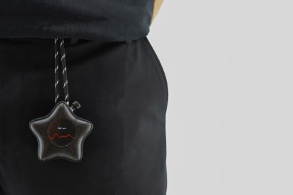 Photo of a black star-shaped Mesh-89 device attached by a tether to a person's waistband