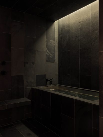 A single shaft of light above a bath highlights the texture of slate