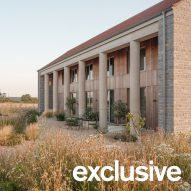 Oblique view along the length of the house showing the row of cylindrical concrete columns and landscaped garden